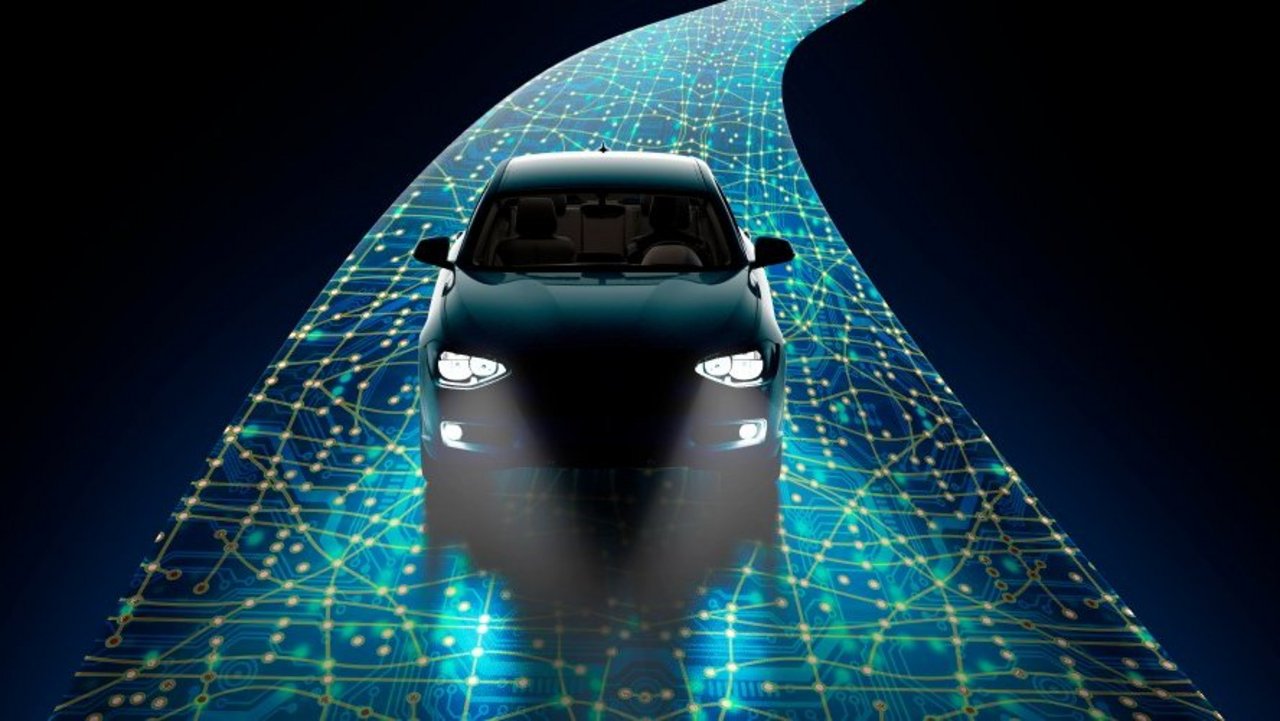 Dunkles Fahrzeug auf einer leuchtenden, digital vernetzten Straße mit Leiterbahnstruktur als Symbol für intelligente und vernetzte Mobilität.