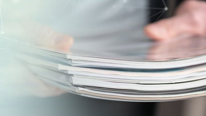 Mann hält einen Stapel Zeitschriften