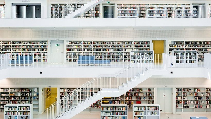 Ein Bild des Innenraums der Stuttgarter Stadtbibliothek. Helle Weiße treppen in einem gebäude mit einem Mittleren hohlen kern an welchen die Stockwerke in Balkonen grenzen 